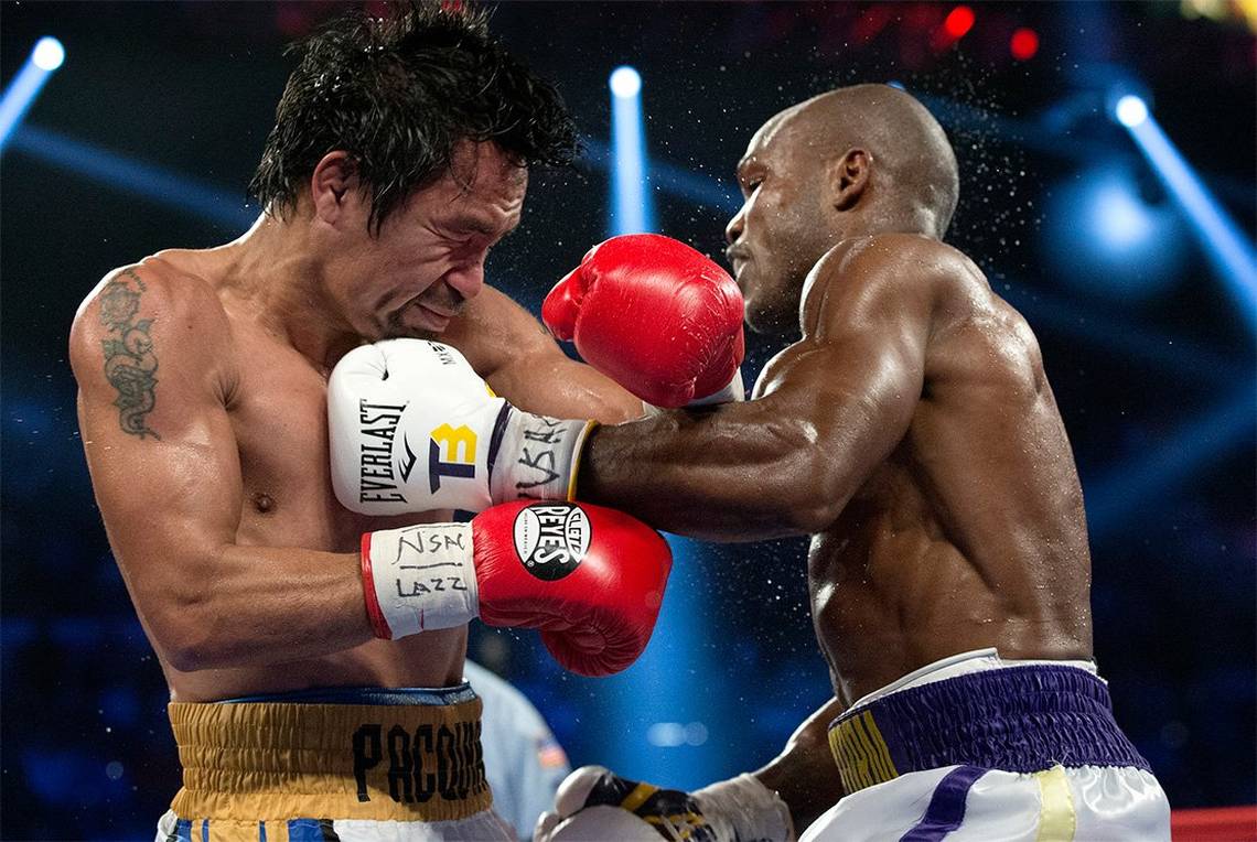 Boxers Manny Pacquiao and Timothy Bradley punch each other in a boxing ring at the MGM Grand.
