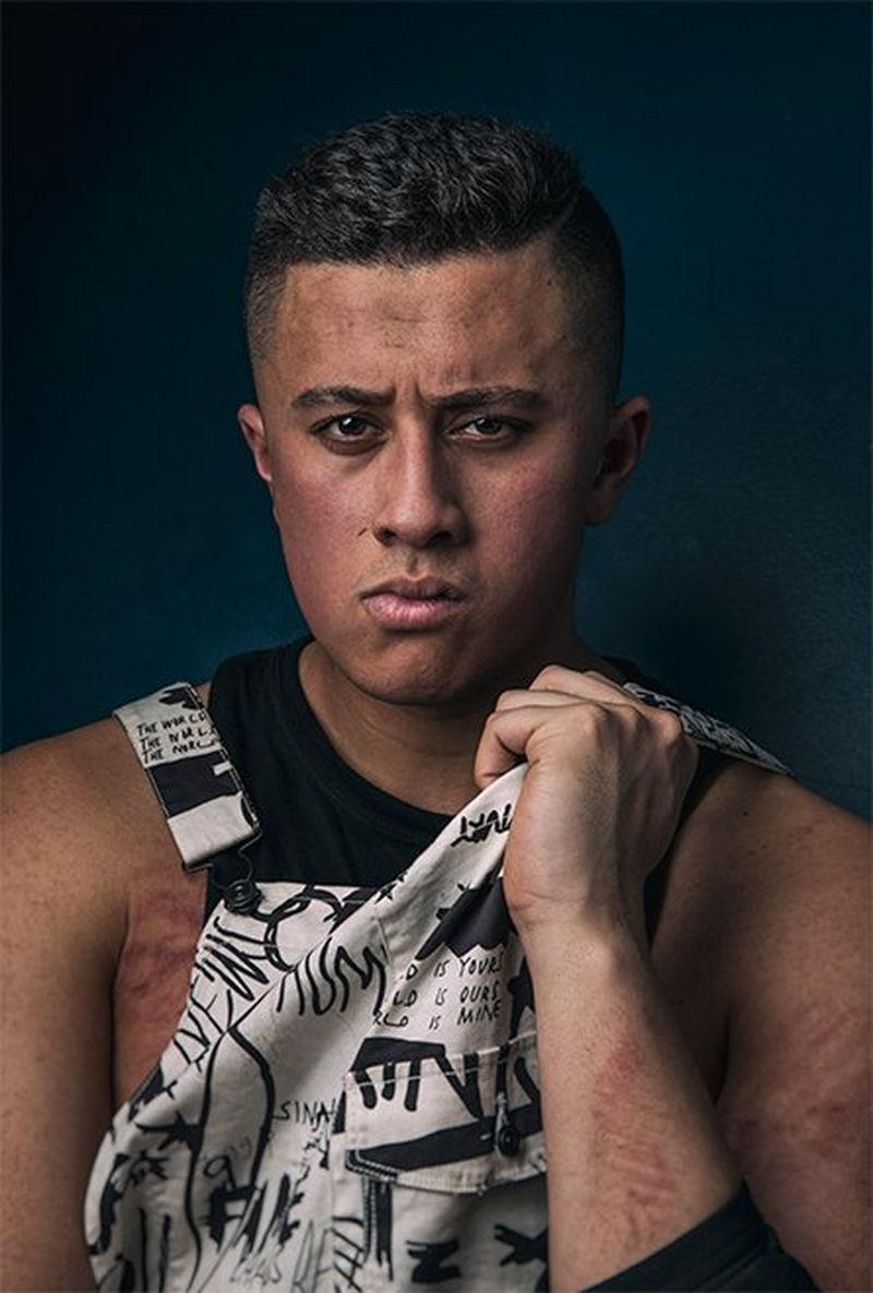 A headshot of wrestler TK Cooper shows him pulling his top up, pouting a little.