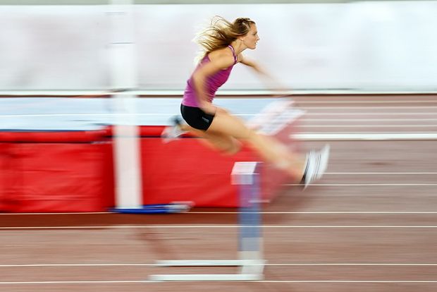 woman jumping over hurdle
