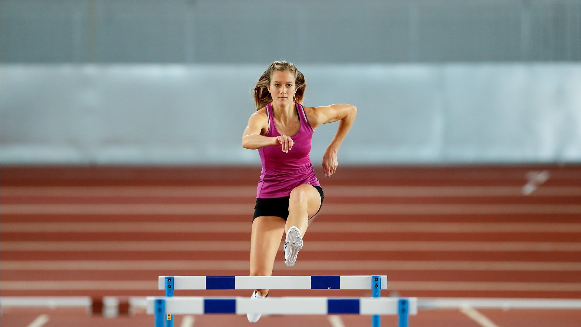 woman jumping over hurdles in sprint