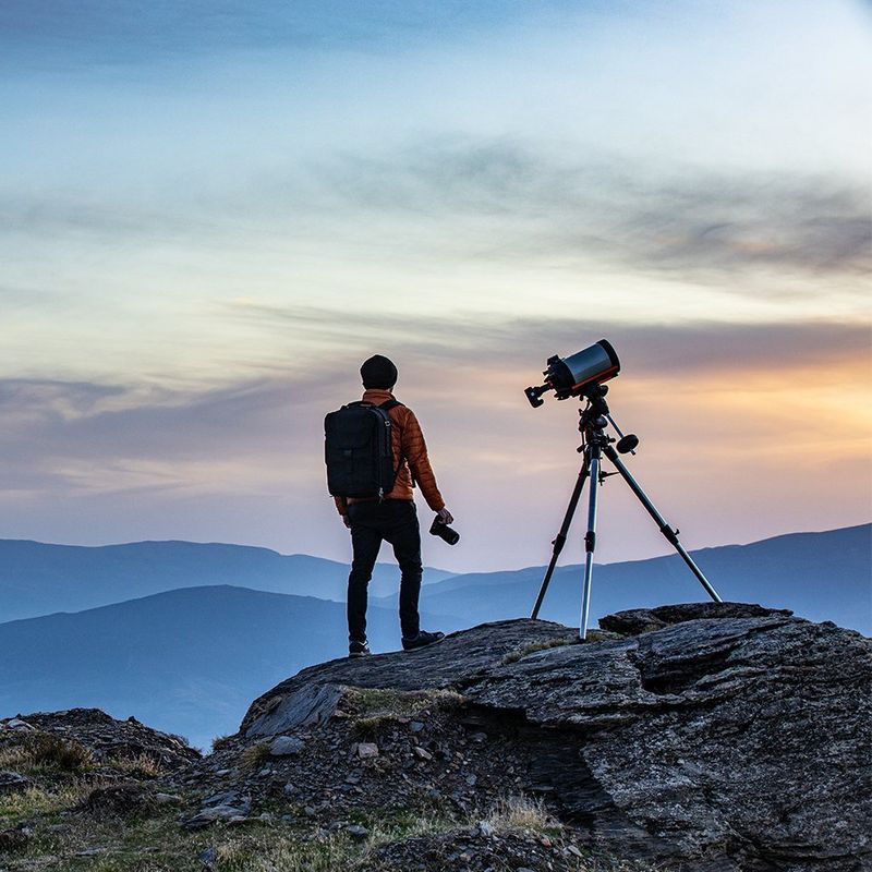 Canon EOS Ra in hand with subject looking at the landscape and another EOS Ra attached to a telescope