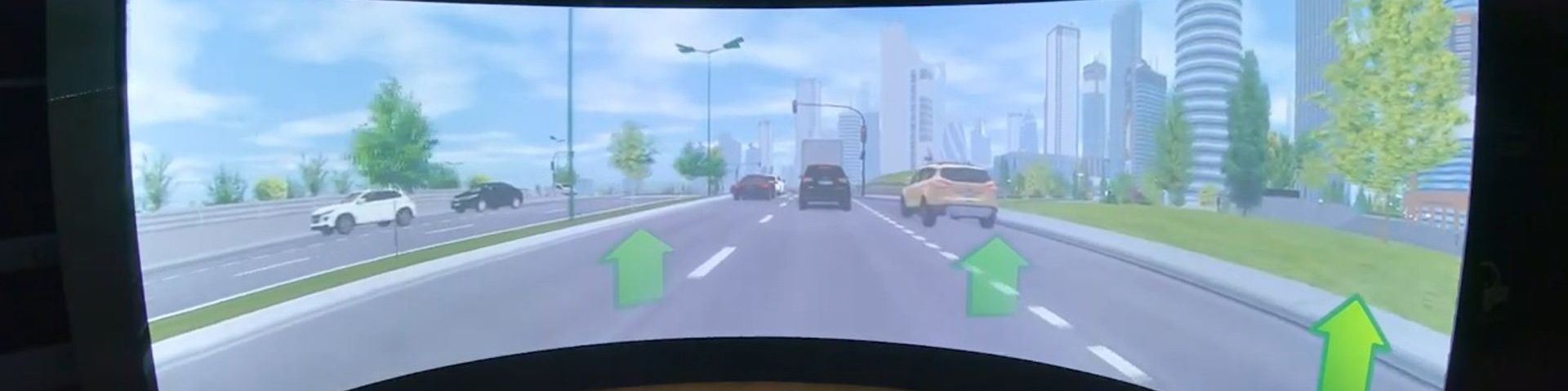 A wide screen depicting a highway with five cars and office buildings running alongside the road to the right.