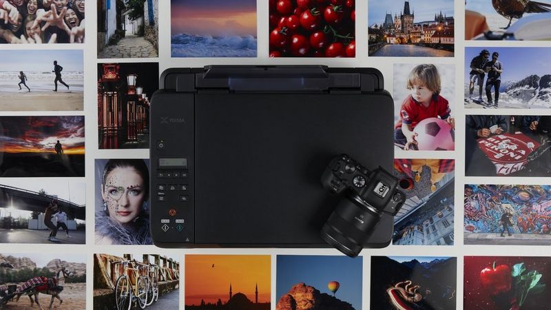 Een Canon-camera en -printer met geprinte foto's op de achtergrond.