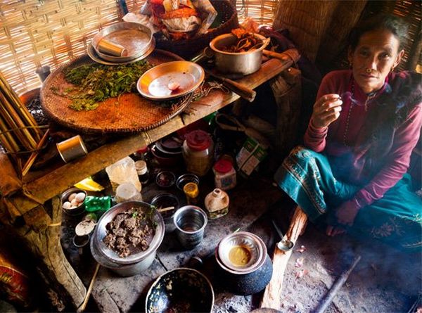 A woman sits on the floor next to shelves and dishes of food.