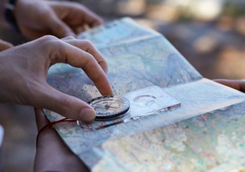 Hands, holding a compass over a map