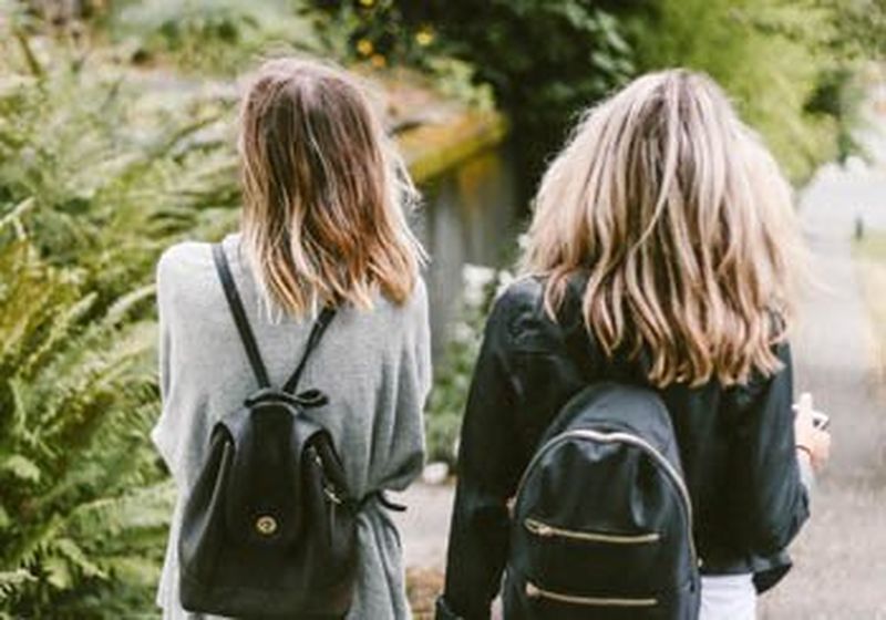 Two young women standing with their backs to the camera