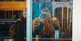 Giuseppe Esposito-Rodrigues taking a photo of a shop window, showing passers by in the reflection.