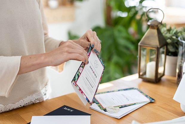 A woman printing off homemade invitations and folding envelopes.