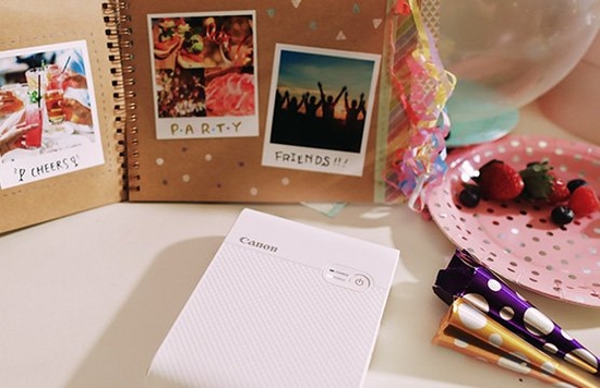 A scrapbook filled with photos printed on a Canon Selphy Square QX10 printer.