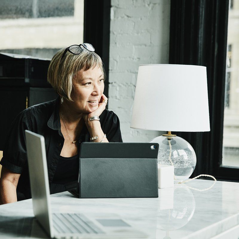 Woman looks out the window while using an iPad on a marble desk