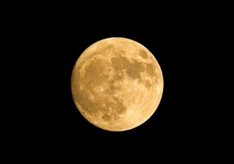 A large, yellow supermoon against a black sky
