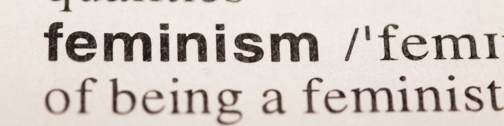 A close up photo of the dictionary definition of feminism. The words shown on the first lineare are ‘Feminism/’femi’. The second line shows the words ‘of being a feminist’.
