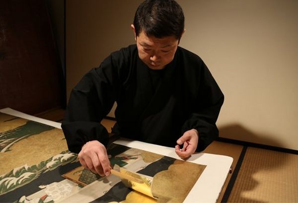 A master craftsman works with gold leaf