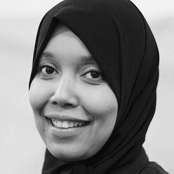 A black and white picture of a smiling woman in a hijab.