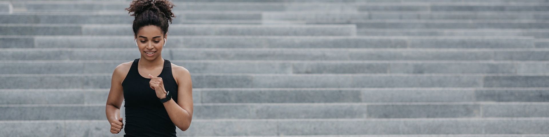 A woman in a black vest runs down a set of concrete steps