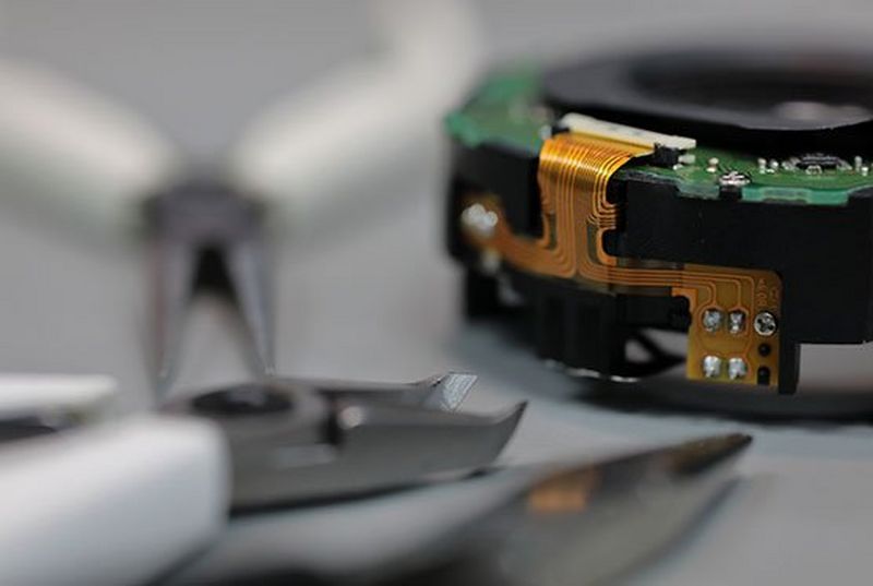 A Canon component with repair tools placed on a desk