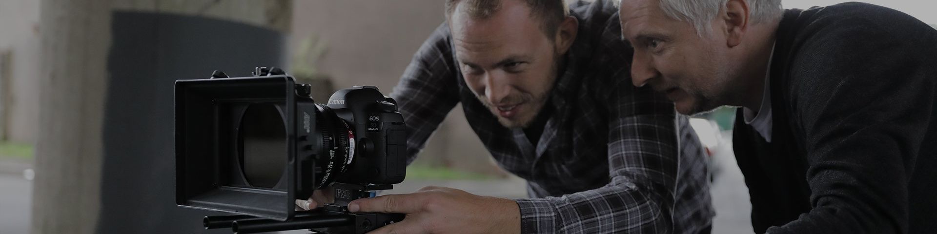 Two camera men inspecting the rear screen of a Canon EOS camera