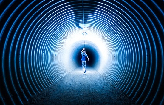 Man running down a tunnel towards a black hole