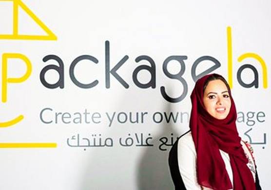 A smiling Doaa bin Thabit stands in front of the logo for Packageha.