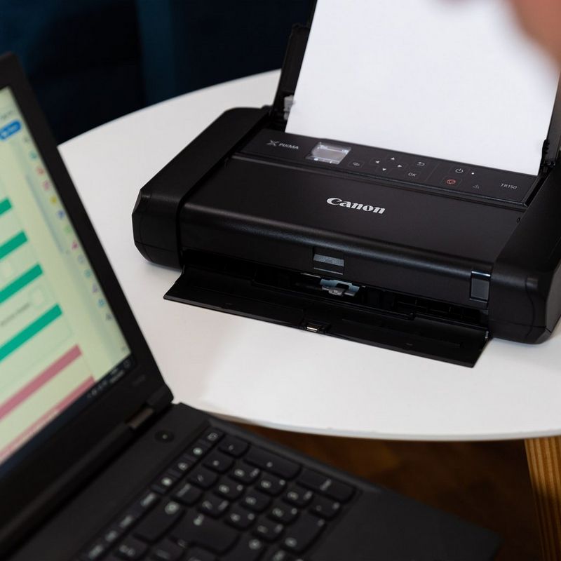 Canon PIXMA TR150 mobiler Tintenstrahldrucker Auf einem Tisch neben einem Laptop
