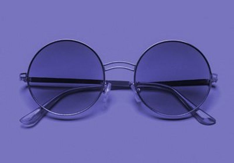 A pair of round ‘John Lennon’ style purple-tinted spectacles on a purple background.