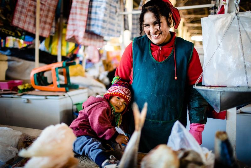 A mother and child working at a colourful street market.