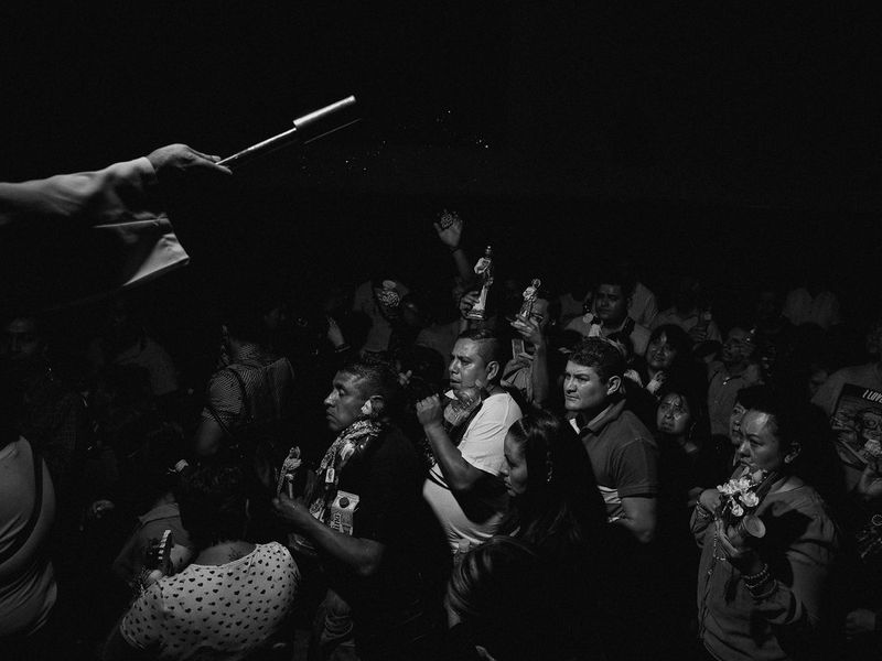 A crowd of people taking part in a pilgrimage in Mexico, many of them holding statuettes.