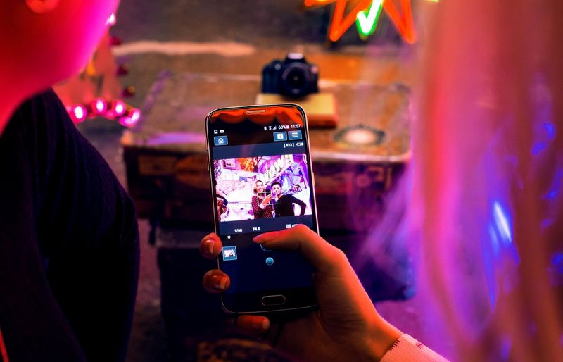 A woman using the Canon Camera Connect app on her smartphone to operate her camera remotely. 