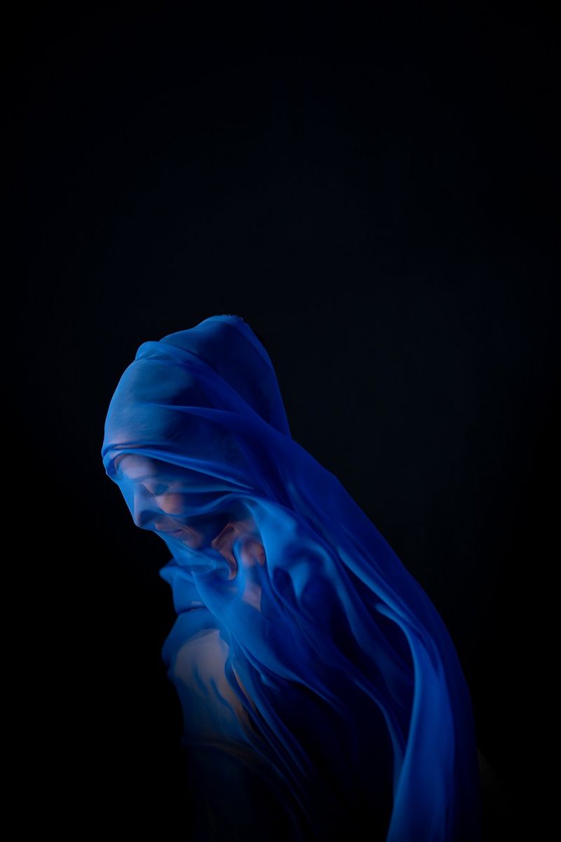 A side profile of a woman draped in sheer blue fabric by Canon Ambassador Clive Booth.