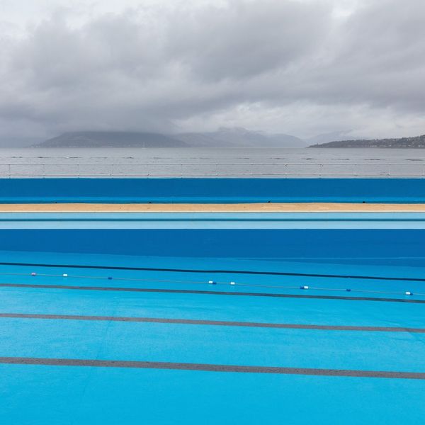 The bright blue waters of Gourock Outdoor Pool in Inverclyde, Scotland, under grey storm clouds.