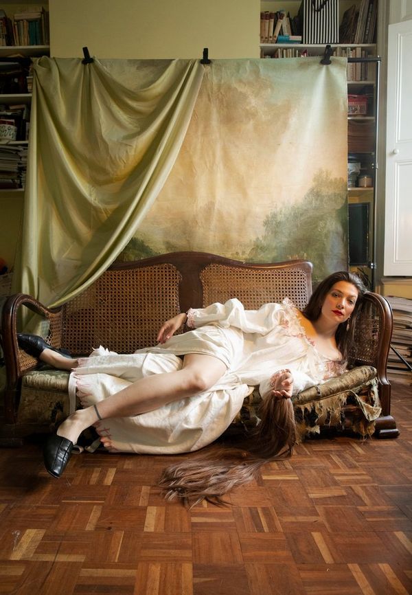Wanda Martin reclines on a low sofa, a sheet of material clipped to a rail behind her.