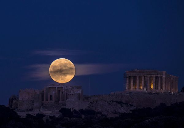 A full moon rising above the Acropolis of Athens, Greece.