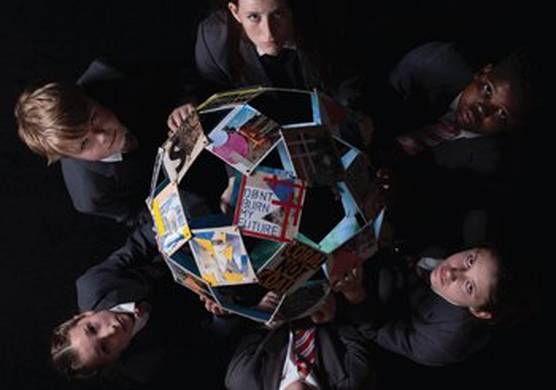 Taken from above, six children hold a globe made of photographs and raise their solemn faces to the camera. The clearest photo, in the center of the globe, displays the words ‘don’t burn my future’.