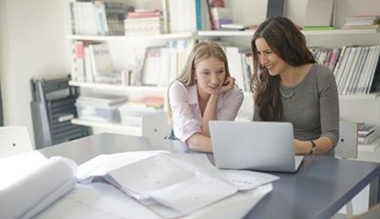 To damer ser på en computer, der ligger en masse papir foran dem, de er ved at skabe effektive kampagner med målbar respons ved hjælp af Canons business værktøjer
