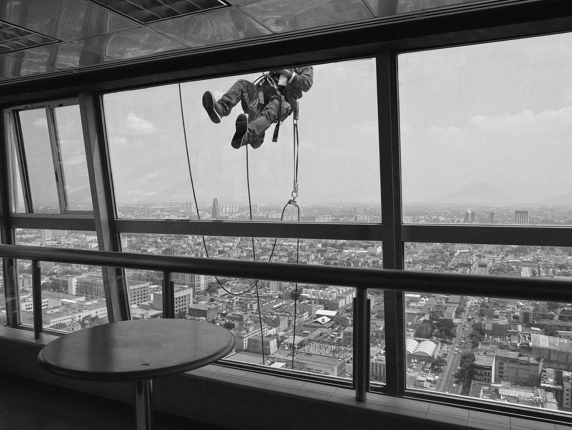A window cleaner outside the 40th floor of the Torre Latinoamericana in Mexico City, with the sprawling city below. Photograph by Jr?me Sessini.