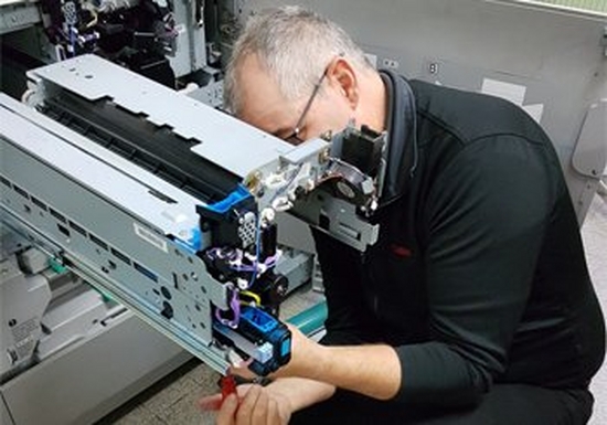 A Canon service engineer fixes the inside of a printer. 