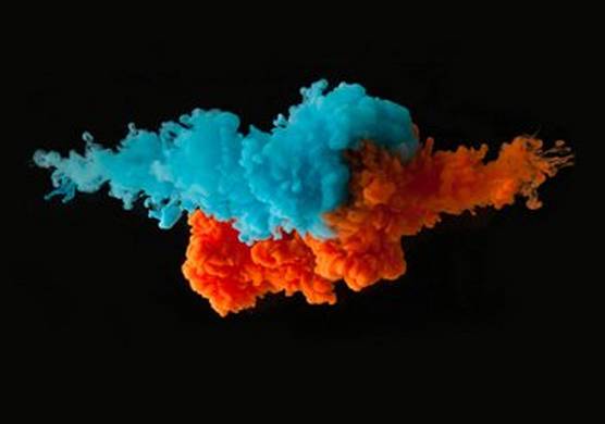 Bright blue and orange ink against a black background, exploding as though in water.