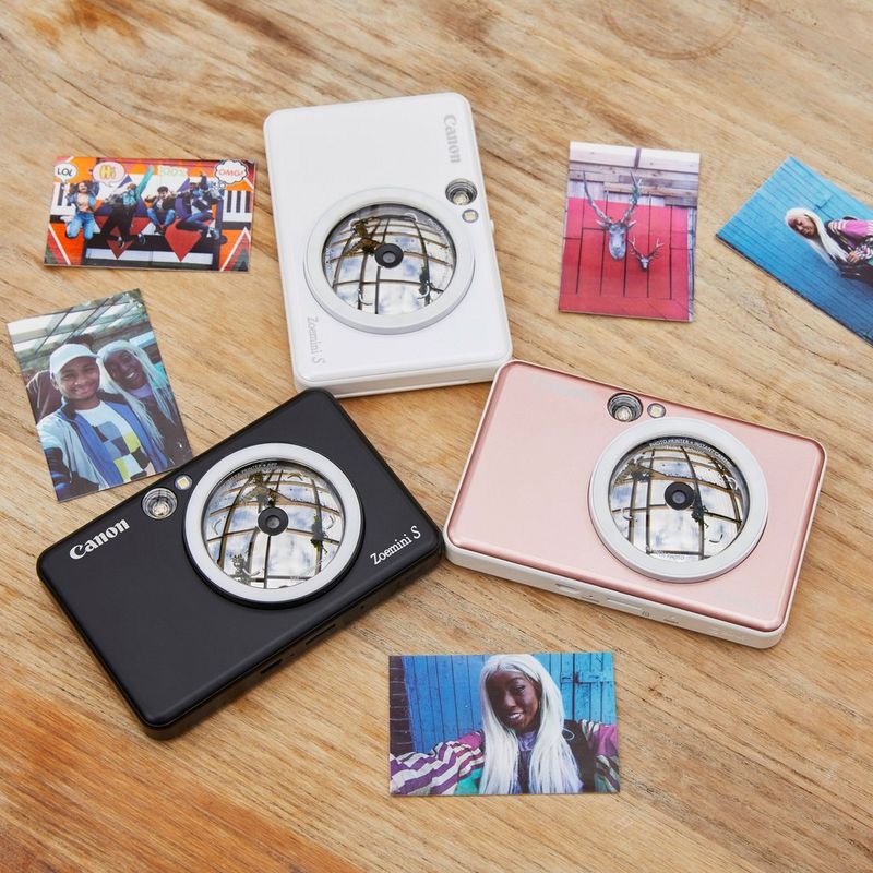 Cámara impresora fotográfica en color instantánea Canon Zoemini S, oro rosa + Diario + Estuche Impresora en un escritorio con impresiones que forman un triángulo
