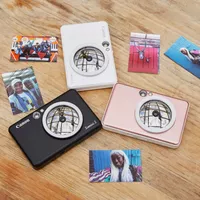 Fotocamera istantanea e stampante fotografica a colori Canon Zoemini S (oro rosa), diario e custodia Stampante in una forma triangolare con stampe su una scrivania