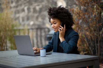 Woman behind laptop working outdoors on a table