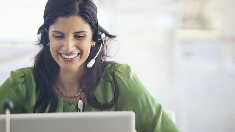 Office professionals smiling while looking at a computer with a head piece on