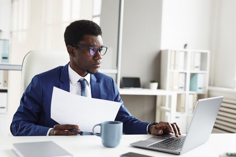 Femme Sur Son Lieu De Travail Regarde La Caméra, Ordinateur Portable Sur Le  Bureau