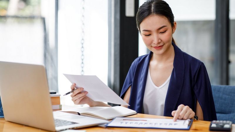 Work professional sitting at her desk smiling and reviewing documents