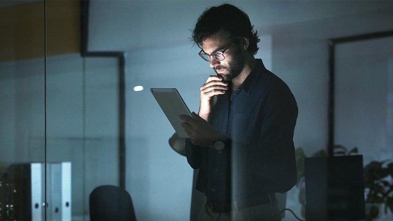 Man standing in an office looking at his smart phone