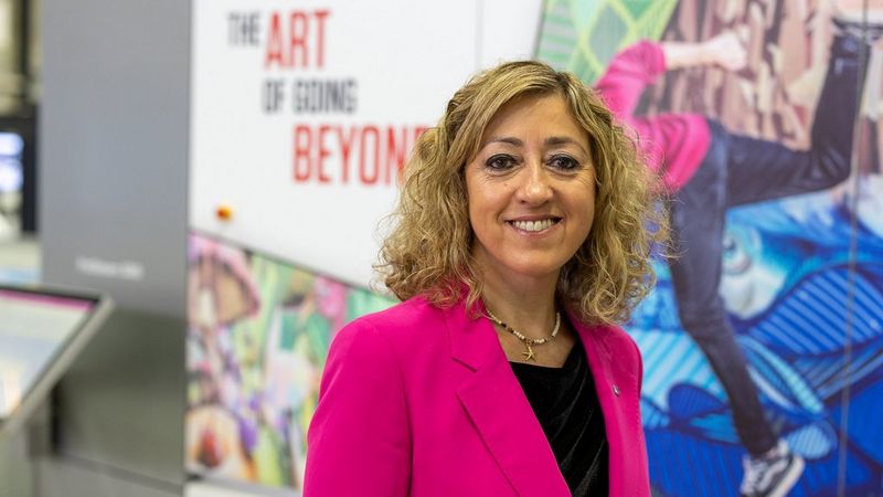 A portrait of Alicia Cifré Trassierra. She wears a magenta jacket over a black blouse and she is smiling.