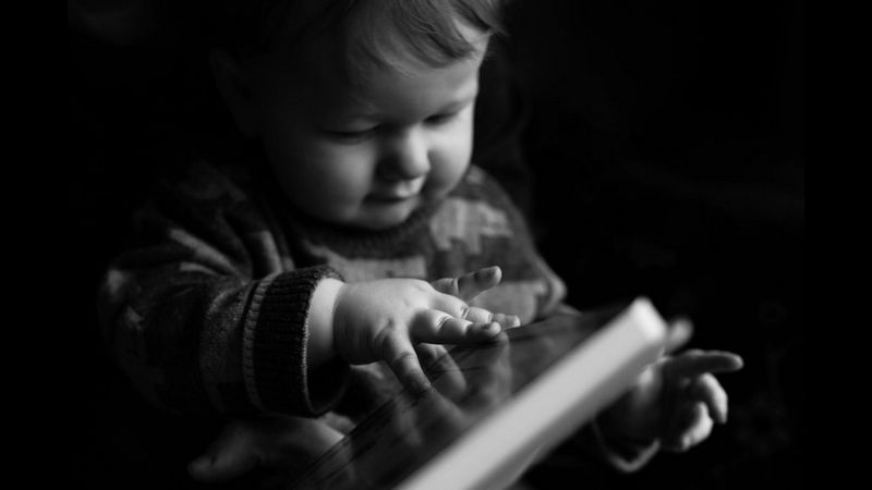 صورة بالأبيض والأسود لطفل يلمس كتابًا.