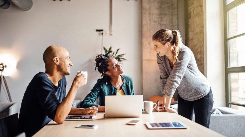 Business colleagues with coffee and laptop at meeting table – Canon UK