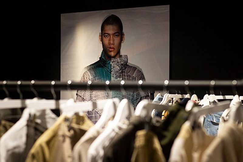 Picture of print outs on the wall behind clothing racks 