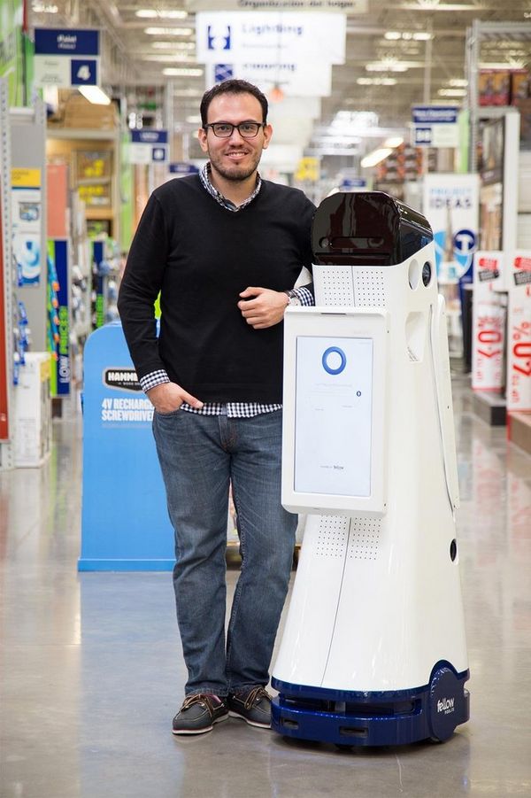 Marco Mascorro standing next to the robot he created.
