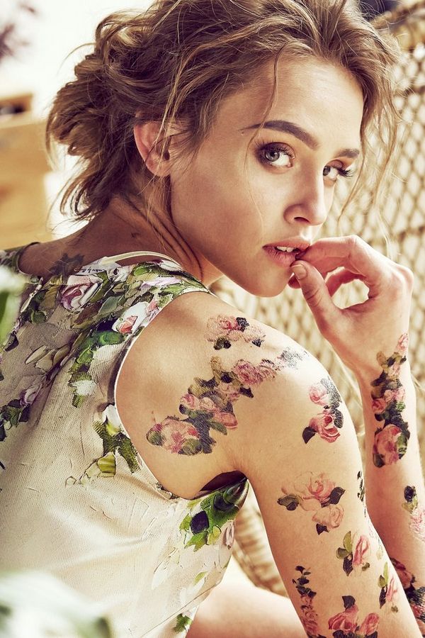 A woman in a floral dress, and with floral tattoos over her arm and shoulder, looks back at the camera. Taken by Jaroslav Monchak on a Canon EOS 5D Mark III.